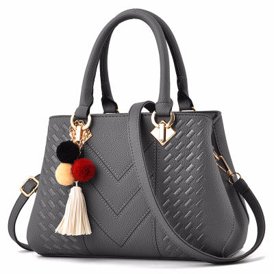 Embossed top handle handbag with pompom